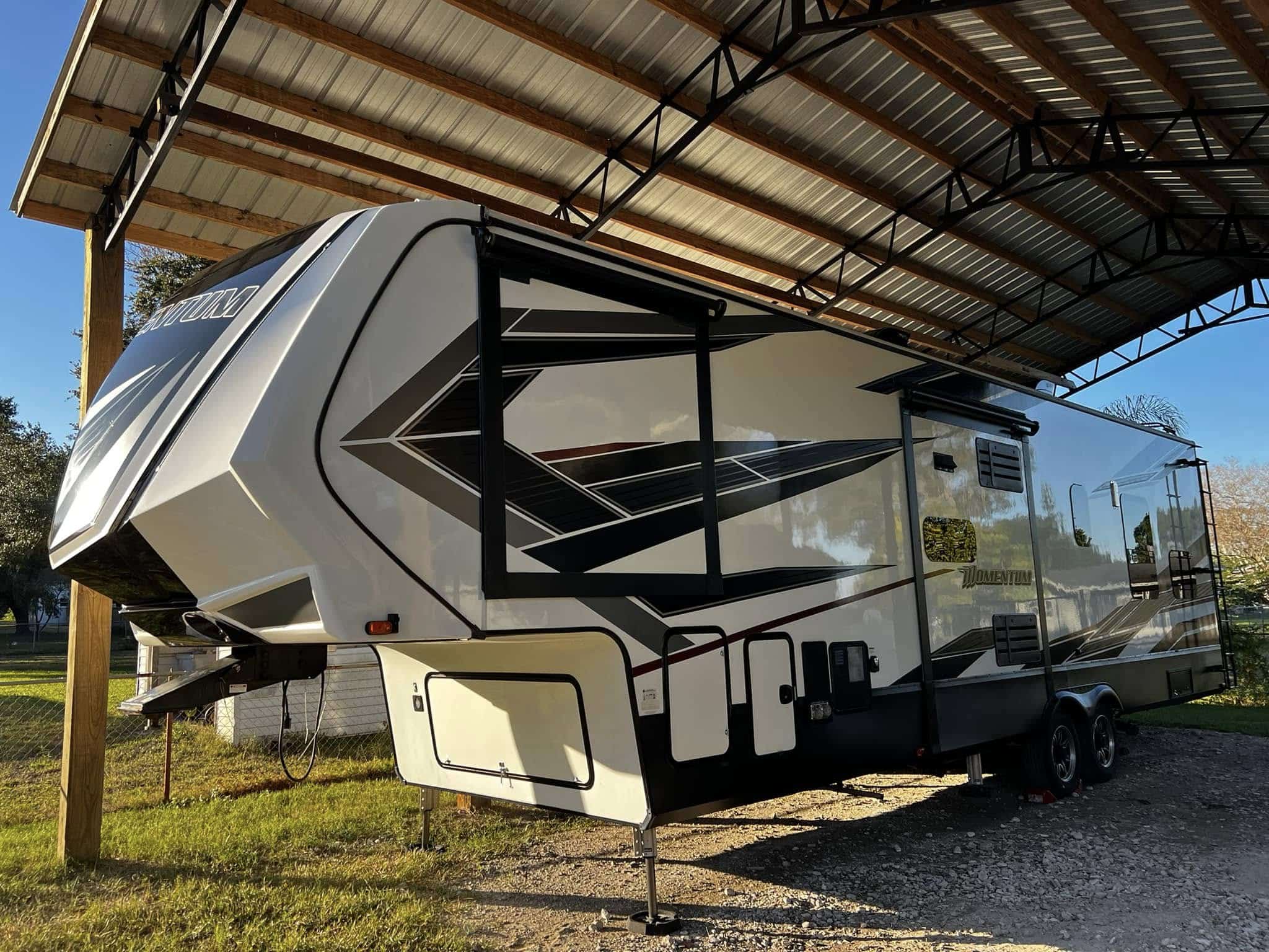 Grand Design Momentum fifth wheel RV with glossy ceramic coating parked under carport