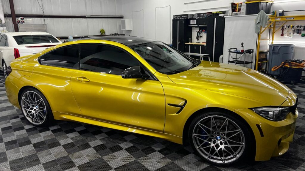 Yellow BMW M4 coupe with dark ceramic vs dyed window tint in detailing garage